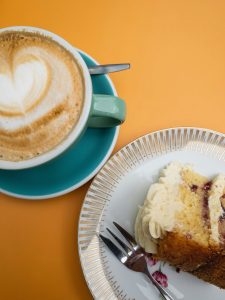 Green coffee cup, heart shaped coffee pattern, slice of cake with cake folk
